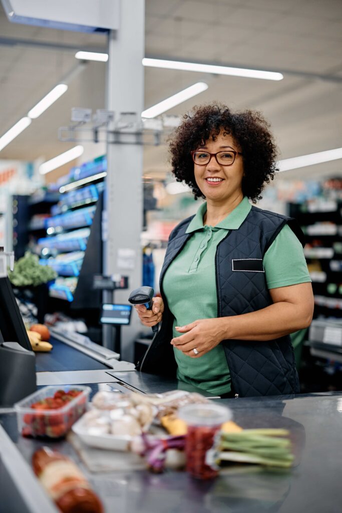 Happy Female Supermarket Cashier Looking At Camera.